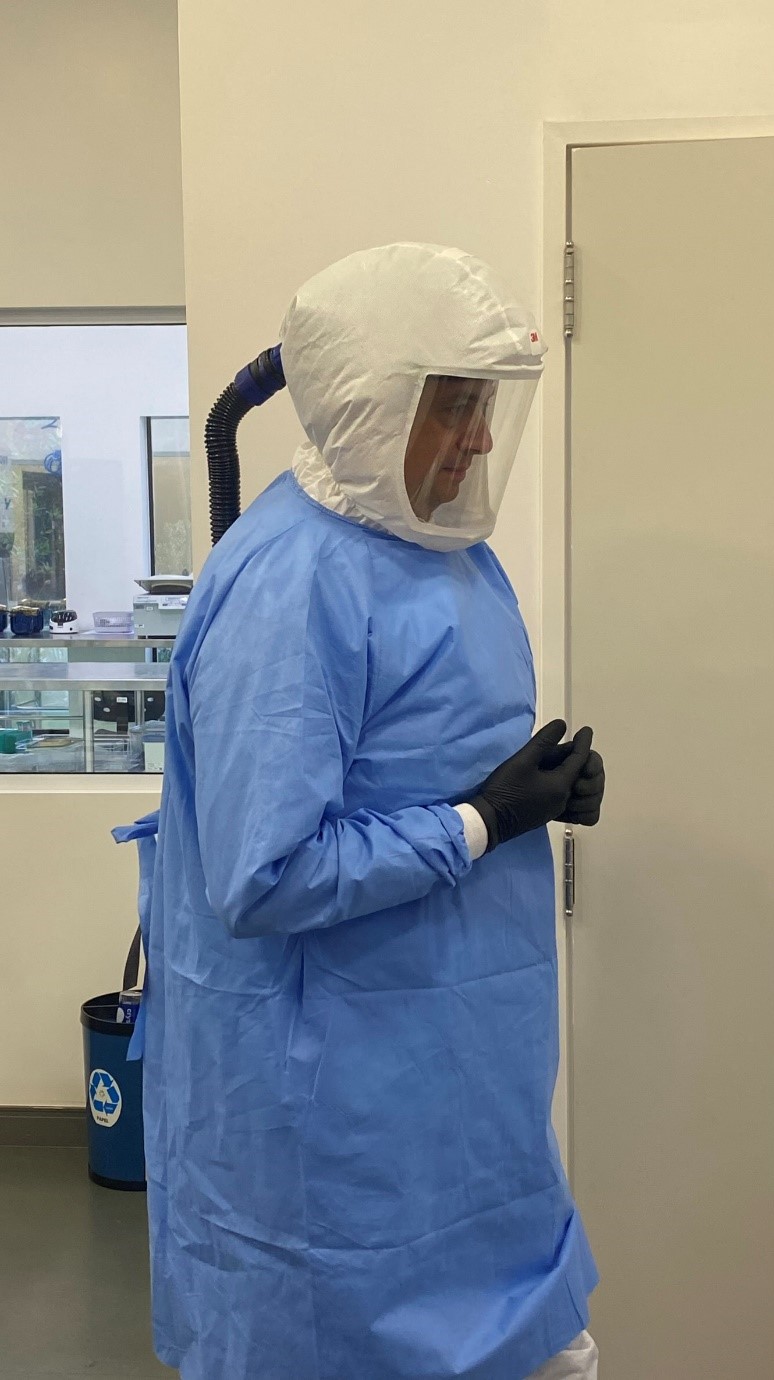 Legenda: Laboratório de treinamento do CNPEM conta com Equipamentos de Proteção Individual (EPIs) para nível 3 de biossegurança. Na foto, profissional em sessão prática utilizando respirador motorizado com filtro HEPA (Créditos: Divulgação/CNPEM)